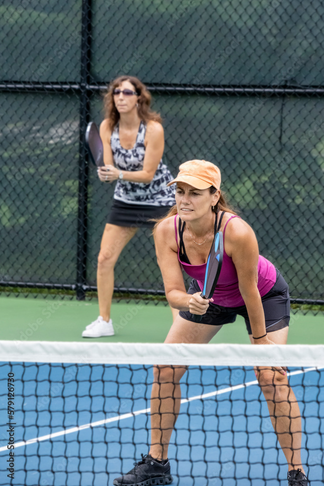 Two pickleball players prepare to hit a ball Two pickleball players prepare to hit a ball