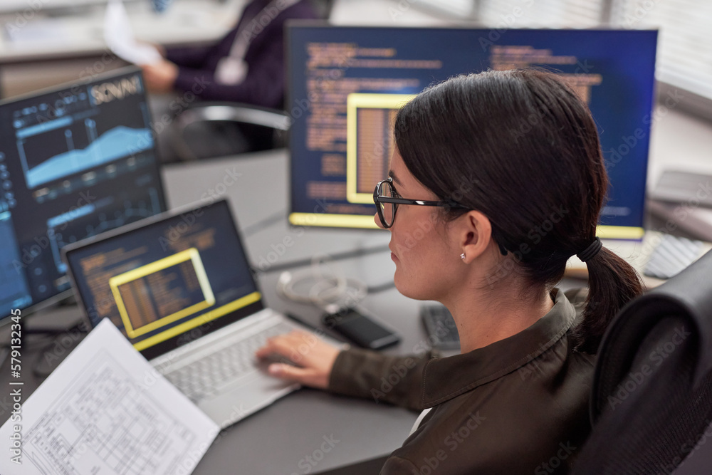 Side view portrait of woman as female IT engineer working with data at desk Side view portrait of woman as female IT engineer working with data at desk