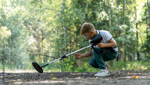 a boy with a metal detector is looking for treasure in the forest photo