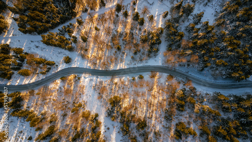 Drone top down on the road and a forest. A bird's eye view of the snowy landscape with the sun shining. Taken on the Jested Ridge in Liberec Region. 