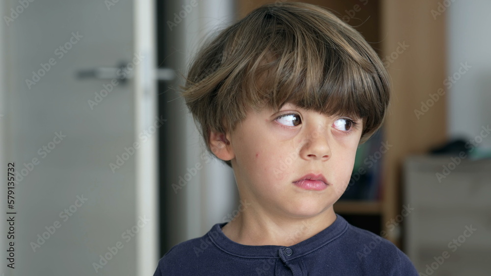Portrait of one pensive young boy looking sideways thinking. Close up face of a child standing indoors with thoughtful expression Portrait of one pensive young boy looking sideways thinking. Close up face of a child standing indoors with thoughtful expression