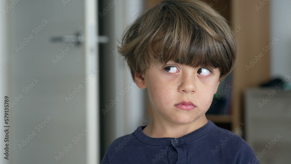 Portrait of one pensive young boy looking sideways thinking. Close up face of a child standing indoors with thoughtful expression Portrait of one pensive young boy looking sideways thinking. Close up face of a child standing indoors with thoughtful expression