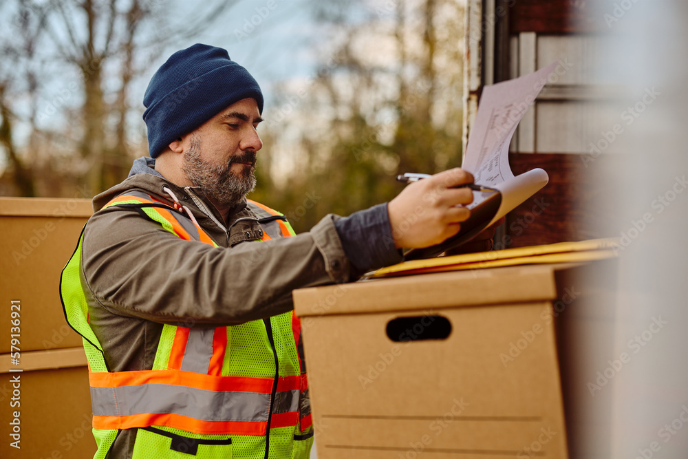 Truck driver checks shipment list while getting ready for ride. Truck driver checks shipment list while getting ready for ride.