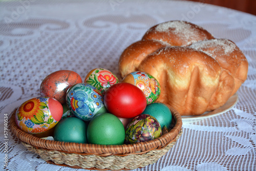 A table with a weave basket with multicolored dyed eggs and a sweet Easter bread