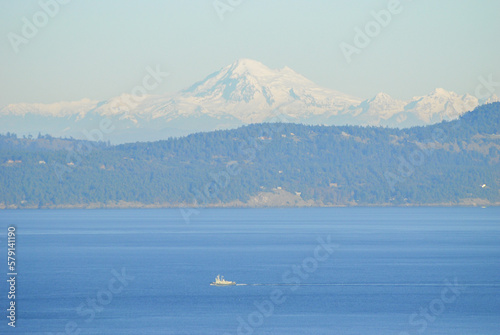 A tugboat traverses and ocean pathway with the San Juan Islands and the beautiful Mount Baker in behind photo