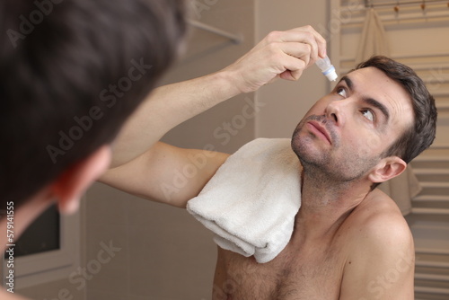Man applying eyedrops in the bathroom 