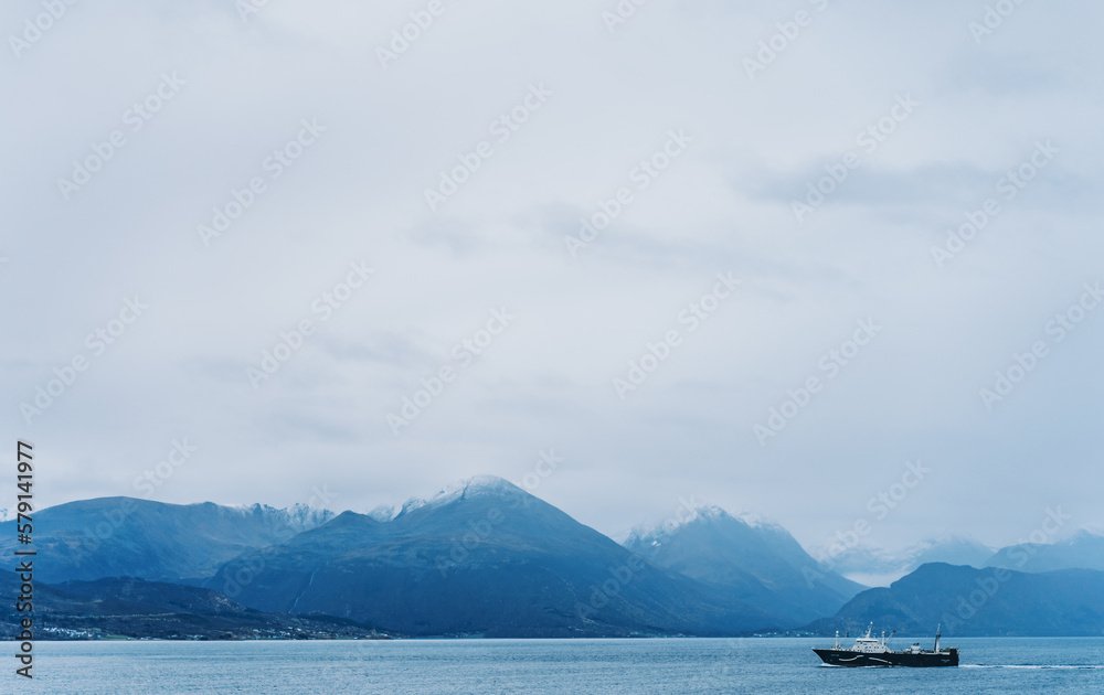 Ein Schiff fährt im Fjord an einem nebeligen Tag Richtung Hafen