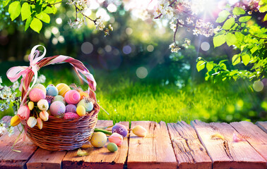 Easter Eggs In Basket On Aged Wooden Table In Spring Garden With Sunlight