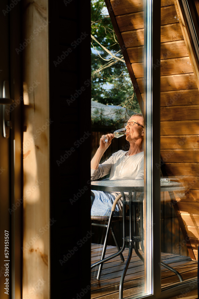 Man sits on terrace in sunny day and drinks prosecco