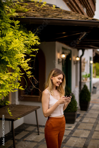Young woman standing in the backyard and using mobile phone