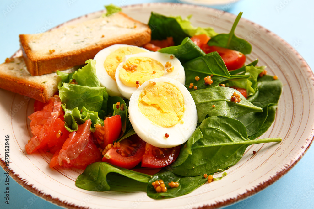 Plate of delicious salad with boiled eggs and salmon on blue background Plate of delicious salad with boiled eggs and salmon on blue background