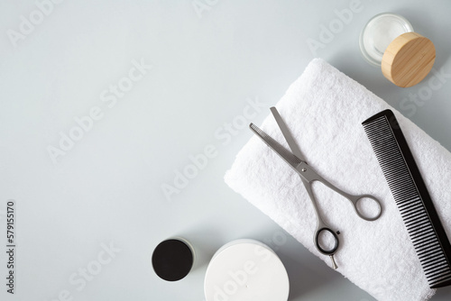 Hairbrush, filleting scissor and jars of creams are on a grey background. View from the top point. Copy space.