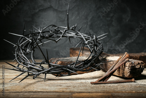 Crown of thorns, nails and cross on wooden table