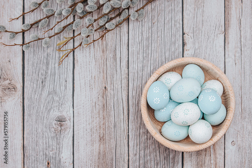 Easter decorations. Easter eggs dyed with pastel colours, bowl, on wooden background