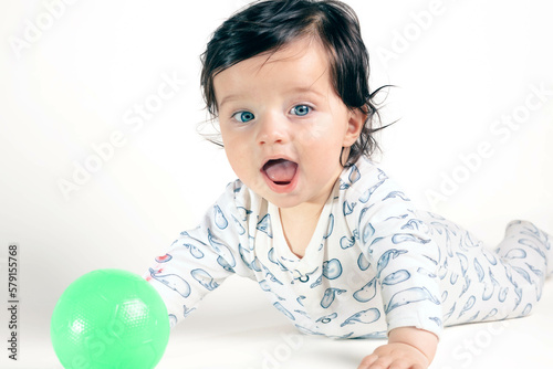 Baby with green eyes playing with a ball