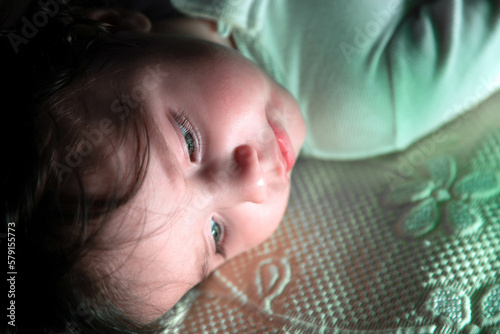 Baby with green eyes lying in bed