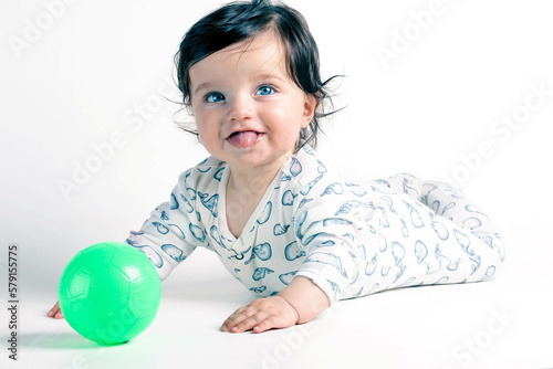 Baby with green eyes playing with a ball