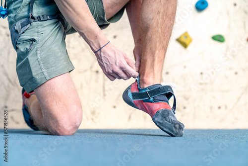 putting on climbing shoes next to the climbing wall