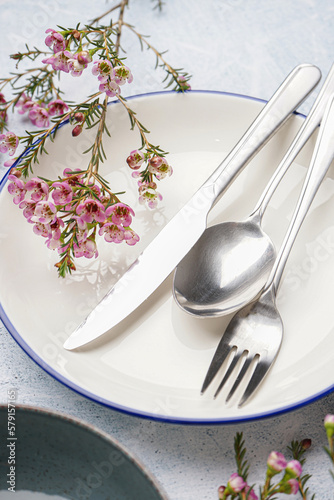 Clean dishes  cutlery and floral decor on grey grunge background