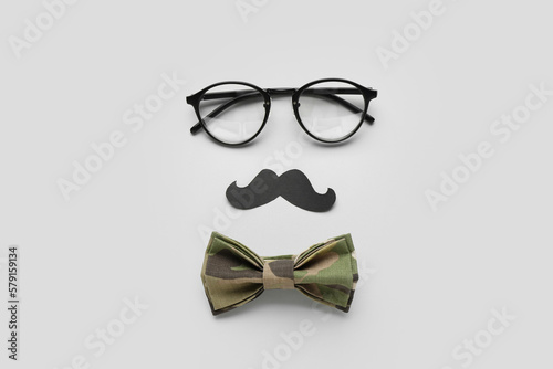 Composition with eyeglasses, paper mustache and bow tie on white background