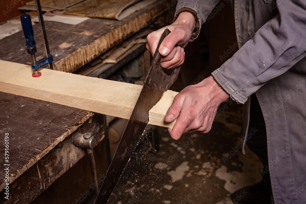 A carpenter works in a workshop with a saw, planer and various tools A carpenter works in a workshop with a saw, planer and various tools