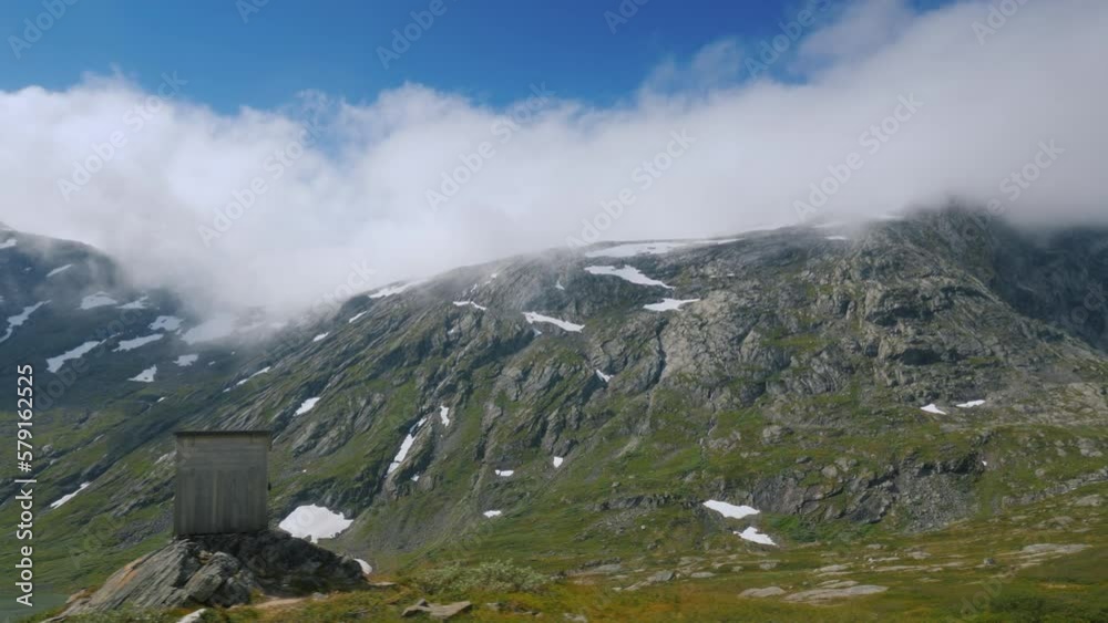Ride near the picturesque mountain landscape of Norway, drive past a lone wooden house. View from car window Ride near the picturesque mountain landscape of Norway, drive past a lone wooden house. View from car window