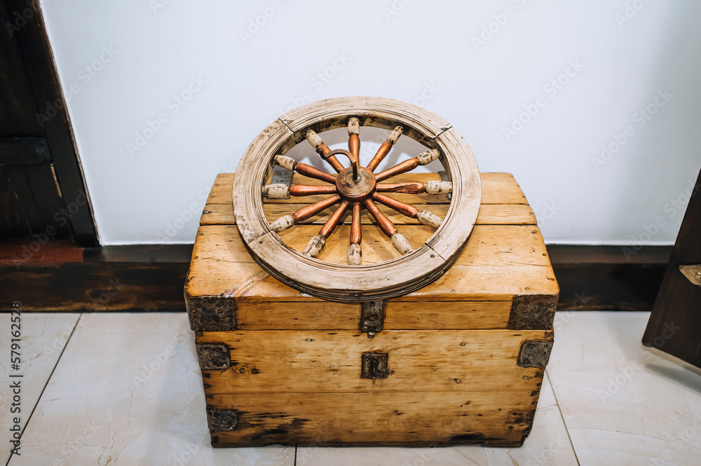 An old wooden wheel from a cart lies on a chest, a treasure chest. Ancient find, old invention.