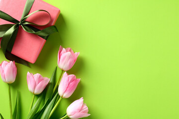 Happy Mothers Day greeting card template. Flat lay gift box with pink tulips on green table.
