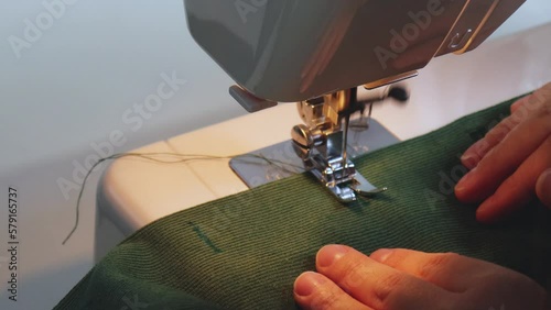 Close-up sewing proccess sewing machine. Side view needle work. Handmade, making handcrafted green velveteen fabric, hand-sewn dress. Top view creating buttonholes for buttons.  manufacturing business photo