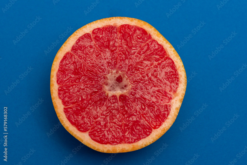 Sliced side of a grapefruit with red pulp isolated on a blue background Sliced side of a grapefruit with red pulp isolated on a blue background