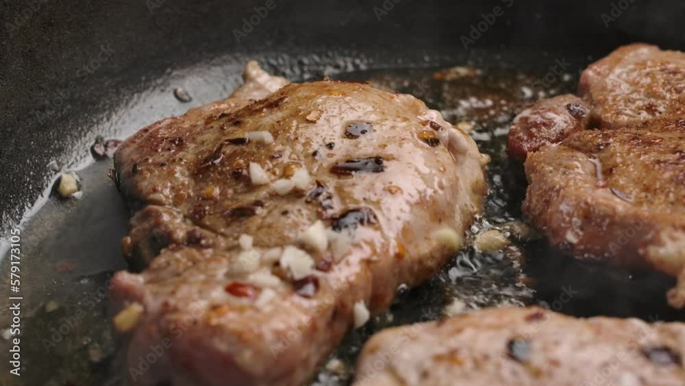 Pieces of garlic fall on steaks roasting in a pan Pieces of garlic fall on steaks roasting in a pan