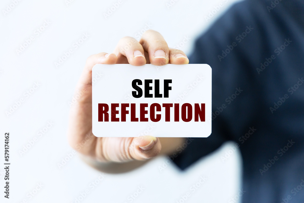 Self reflection text on blank business card being held by a woman's hand with blurred background. Business concept about self reflection. Self reflection text on blank business card being held by a woman's hand with blurred background. Business concept about self reflection.