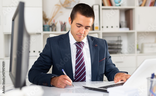 Successful businessman working with papers and laptop in office
