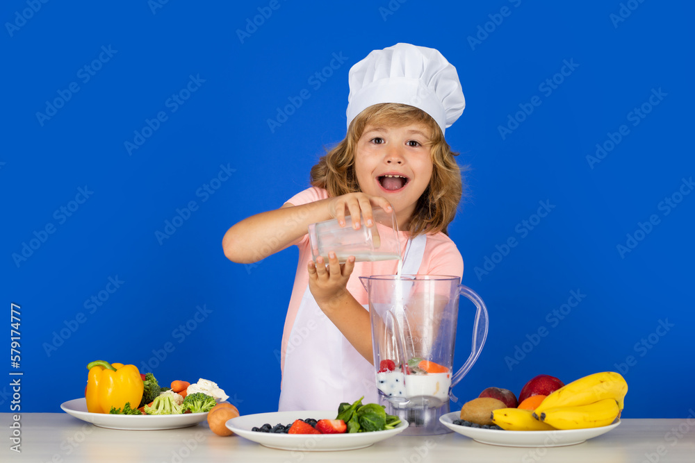 Excited funny chef cook cooking milk shake smoothie. Portrait of chef child in cook hat. Cooking at home, kid boy preparing food from vegetable and fruits. Healthy eating. Excited funny chef cook cooking milk shake smoothie. Portrait of chef child in cook hat. Cooking at home, kid boy preparing food from vegetable and fruits. Healthy eating.