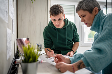 One student teenage caucasian man study learn with help of his tutor professor or mother senior woman at home having private lesson to prepare for exam education concept real people copy space