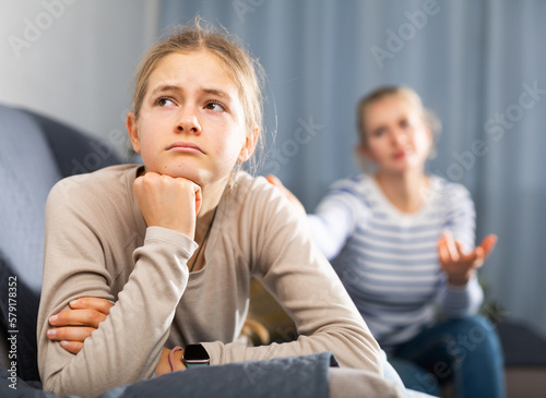Foto Sad female and daughter sitting at sofa and having quarrel at home