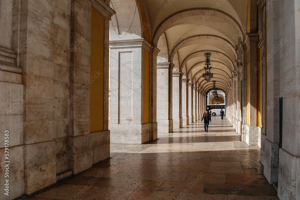 Colonnade. Lisbon. Portugal. The figure of an elderly woman walking through the colonnade.