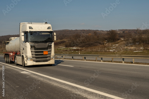 Isothermal Tank truck driving on highway. Oil and Gas Transportation and Logistics. Metal chrome cistern tanker with petrochemicals products. Liquid Chemical Freight. © Bojan