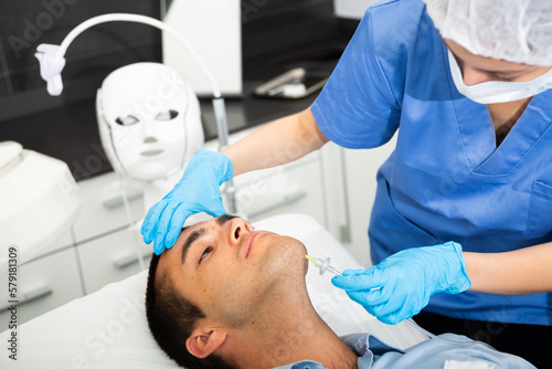 Portrait of male patient during cosmetology procedure in beauty clinic  getting carbon dioxide injections for face skin rejuvenation