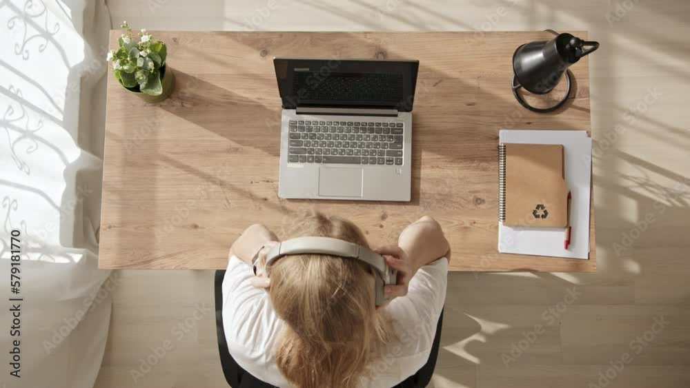 young blonde girl freelancer takes off her headphones and fall asleep at office desktop. Sleep at work in middle of day. Top down view of tired worker from home.