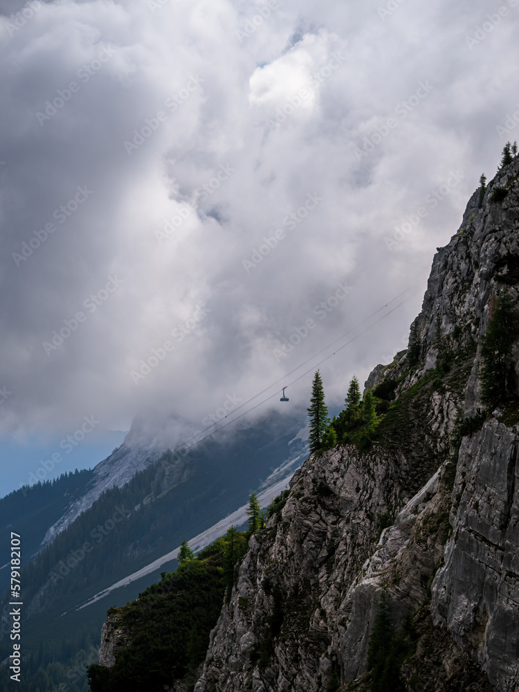 Zugspitze cable car going up the mountain with rocks cloudy weather pine trees