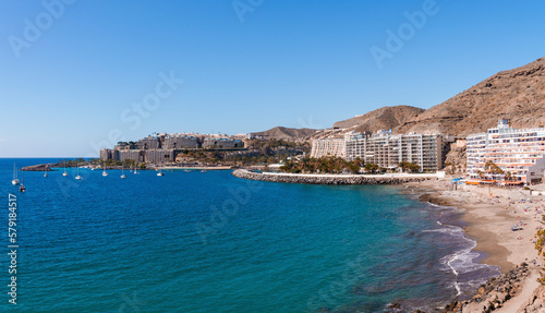 Beautiful seascape with sailboats on water surface and buildings with mountain along the seashore at Gran Canaria, Spain