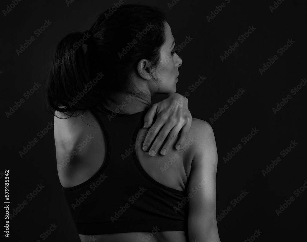 Beautiful sport woman holding and massage the hand the shoulder and neck on dark background. Black and white. Closeup Beautiful sport woman holding and massage the hand the shoulder and neck on dark background. Black and white. Closeup