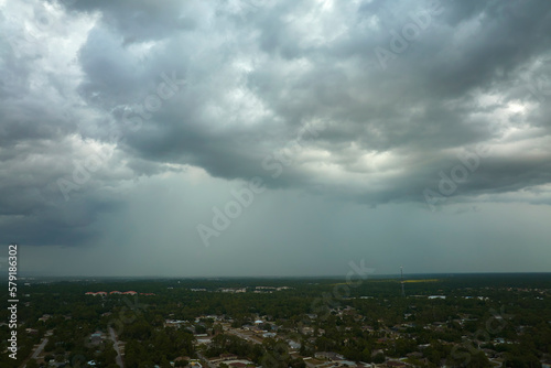 Dark stormy clouds forming on gloomy sky before heavy rainfall over suburban town area © bilanol