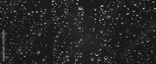 Atmospheric minimal grayscale backdrop with rain droplets on glass. Wet window with rainy drops and dirt spots closeup. Blurry minimalist monochrome background of dirty window glass with raindrops.