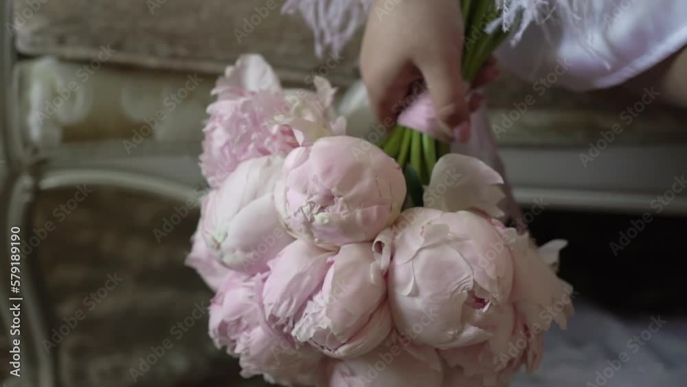 Female in dress hold in hands bouquet with ribbons of pink peonies flowers. Gift for a woman, holiday, wedding bouquet of the bride. Floristics. Female in dress hold in hands bouquet with ribbons of pink peonies flowers. Gift for a woman, holiday, wedding bouquet of the bride. Floristics.