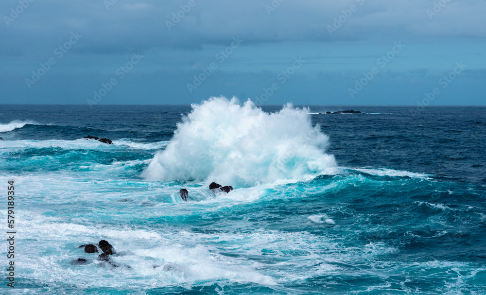 Fototapeta premium Strong waves on the ocean hitting some rocks and creating water foam
