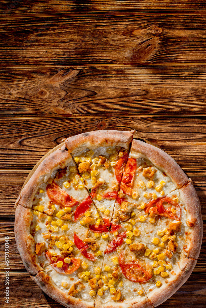 Pizza for children on a cream base with chicken fillet, tomatoes, corn and mozzarella cheese on wood background