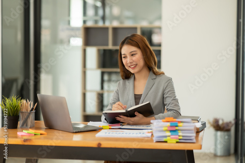 Young Asian businesswoman holding graph on financial business, looking at work © Thitisak