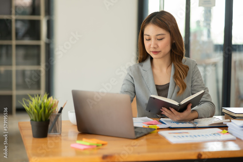 Young Asian businesswoman holding graph on financial business, looking at work